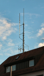Rundstrahlantenne auf einem Hausdach. Die Antenne ist rechts, links ist eine Blitzfangstange (Lauffen)